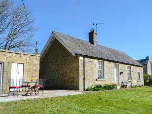 a building with a table and chairs in front of it at Keepers Cottage Burradon in Sharperton