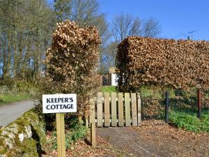 a sign in front of a house with a hedge at Keepers Cottage Burradon in Sharperton