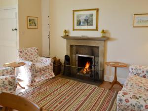 a living room with a fireplace and two chairs at Keepers Cottage Burradon in Sharperton +9 photos