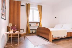 a bedroom with a bed and a chair and a window at Casa Hollaj in Vladimir