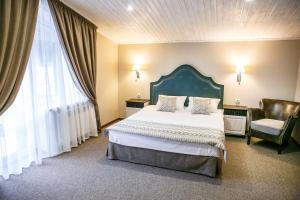 ein Schlafzimmer mit einem großen Bett und einem Stuhl in der Unterkunft Andersen Hotel in Dombai