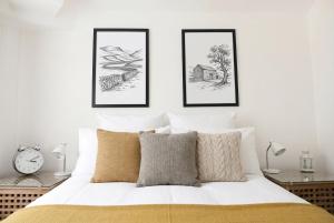 a white bedroom with three drawings on the wall at Willow Cottage in Pateley Bridge