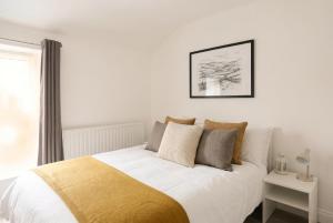 a bedroom with a bed with white sheets and pillows at Willow Cottage in Pateley Bridge +10 photos