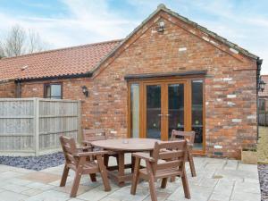 a patio with a table and chairs in front of a brick building at George's Gaff - E4432 in Ingoldmells