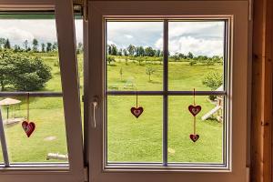 a window with hearts hanging from it with a view of a field at Waldlust in Abtsgmünd +2 photos