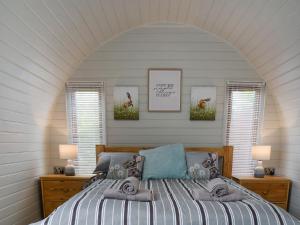 a bedroom with a bed with two windows and two pictures at Laurel Pod - Uk47203 in Westhead