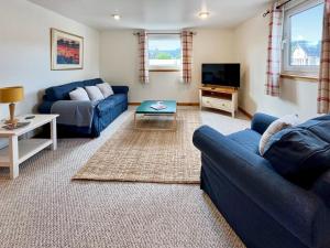 a living room with a blue couch and a tv at Heathergems Apartment in Pitlochry