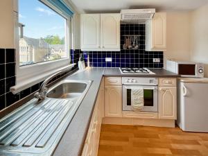 a kitchen with a sink and a stove and a window at Heathergems Apartment in Pitlochry +9 photos