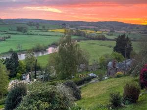 a sunset over a green field with a house and a river at Wye Nest in Fownhope