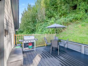 a patio with a grill and an umbrella on a deck at Wye Nest in Fownhope