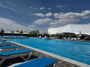 a large swimming pool with blue chairs and umbrellas at U Samogo Sinego Moria in Zatoka