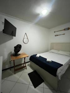 a bedroom with a bed and a table with a television at Preservar hostel in Cabo Frio