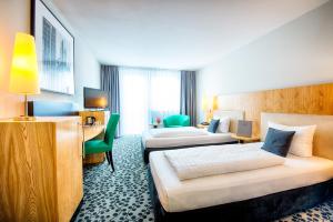 a hotel room with two beds and a desk at Four Points by Sheraton Offenbach Plaza in Offenbach