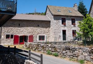 an old stone house with red doors on a street at Digitales en margeride in SAINT DENIS EN MARGERIDE