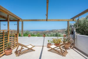 a patio with two wooden chairs and potted plants at Lydia Guest House in Palekastron