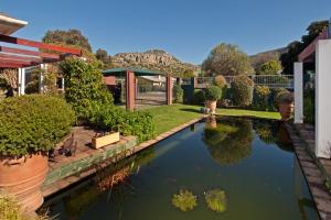 un jardín con un estanque con árboles y arbustos en Brown Jug Guest House, en Hermanus