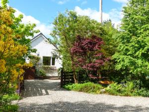 a white house with a fence and some trees at Bo Nan Taigh Cottage in Aberfoyle