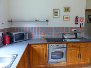 a kitchen with a stove and a microwave at Bo Nan Taigh Cottage in Aberfoyle +7 photos