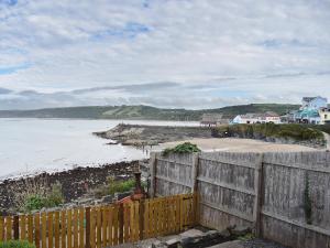a wooden fence next to a beach with the ocean at Seadrift in New Quay