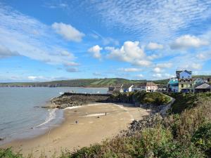 a beach with people on the sand and houses at Seadrift in New Quay