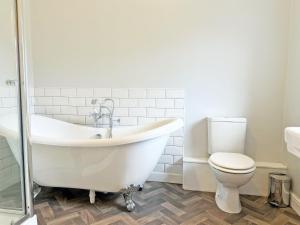 a white bathroom with a tub and a toilet at Leaderfoot Cottage in Selkirk