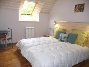 a bedroom with a large white bed with a window at L'écurie in Cohiniac