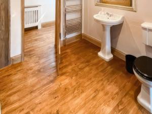 a bathroom with a sink and a toilet and wooden floors at Stewards Granary - Uk48306 in Berwick-Upon-Tweed +3 photos
