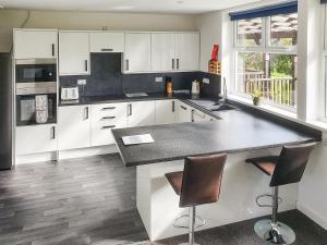 a kitchen with white cabinets and a black counter top at Classroom Two - Uk48651 in Lifton