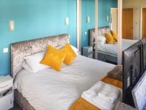 a bedroom with a bed with yellow pillows and a mirror at Classroom Two - Uk48651 in Lifton +6 photos