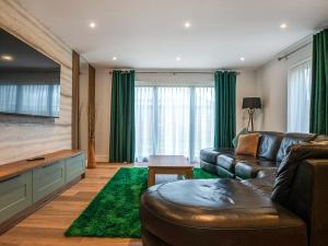 a living room with a leather couch and a green rug at 12 Galloway - Ukc8975 in Warkworth
