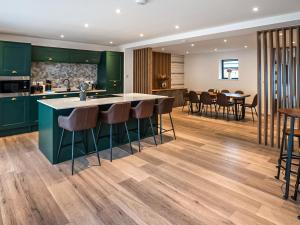 a kitchen with green cabinets and a counter with bar stools at 12 Galloway - Ukc8975 in Warkworth