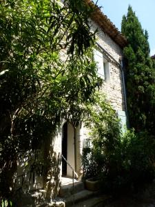 a stone house with a white door and trees at Olea in Vaison-la-Romaine