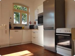 a kitchen with white cabinets and a stainless steel refrigerator at Fewo-Am-alten-Bahnhof in Tangerhütte
