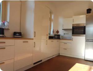 a kitchen with white cabinets and a refrigerator at Fewo-Am-alten-Bahnhof in Tangerhütte +8 photos