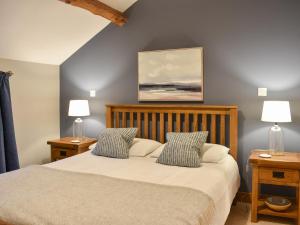 a bedroom with a bed with two night stands and two lamps at Pippa's Cottage - Uk42332 in Little Blencow