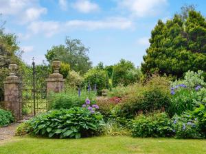 a garden with a gate and a bunch of flowers at Gilminscroft Gatehouse in Sorn