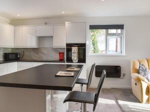 a kitchen with white cabinets and a black table and chairs at Classroom One - Uk48650 in Lifton