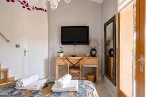 a bedroom with a bed and a desk with a television at Cap Anguilla, chambre d'hôtes in Carnoux