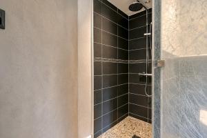 a bathroom with a shower with black tiles at Cap Anguilla, chambre d'hôtes in Carnoux +15 photos