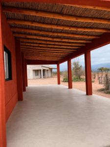 a wooden pavilion with a building in the background at Talahuasto in Los Baldecitos