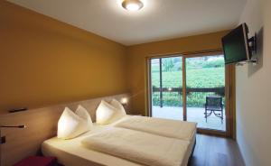 a bedroom with a bed with a television and a balcony at Highlight Apartments in Appiano sulla Strada del Vino
