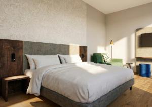 a bedroom with a large bed and a green chair at Lasalt - Mountain Legends Hotel in Ischgl