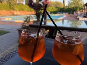 Zwei Getränke stehen auf einem Tisch in der Nähe eines Swimmingpools. in der Unterkunft Il Colombo in Certaldo