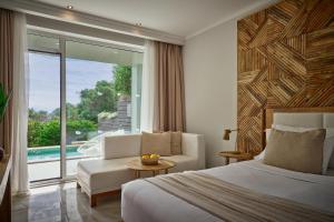 a hotel room with a bed and a couch and a window at Mythos Palace Resort - Adults Only in Boukari +40 photos