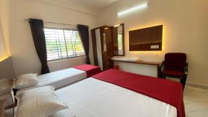 two beds in a room with a desk and a chair at Sri Durga Residency in Subrahmanya