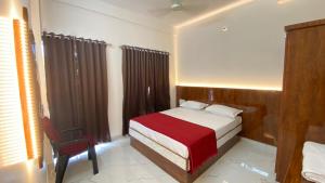 a bedroom with a bed and a chair in it at Sri Durga Residency in Subrahmanya +10 photos
