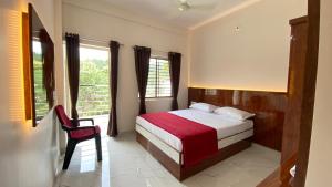 a bedroom with a bed and a chair and a window at Sri Durga Residency in Subrahmanya