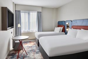 a hotel room with two beds and a table at Leonardo Hotel Newcastle in Newcastle upon Tyne +41 photos