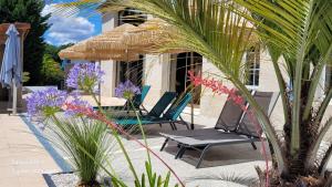 a patio with two chairs and an umbrella and flowers at Les Cuves - Saintes - Chambres d'hôtes et gîte in Saintes