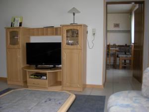 ein Wohnzimmer mit einem TV und einem Entertainment-Center in der Unterkunft Ferienwohnung Steinebach in Daun